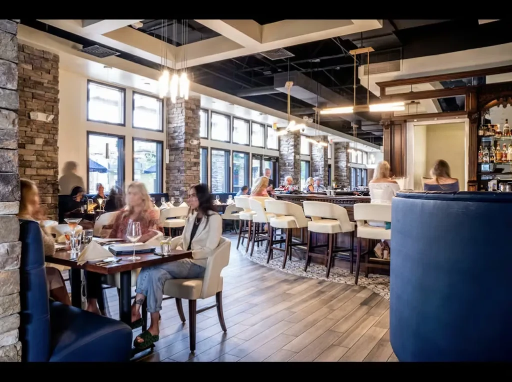 Modern restaurant interior with warm lighting, a bar, and blurred patrons.