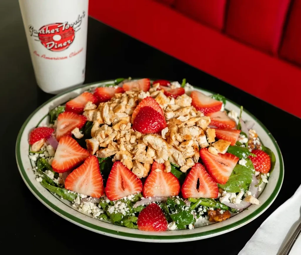 Chicken salad with strawberries, crumbled cheese, nuts, and red onion.