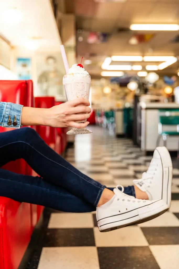 Hand holding a whipped cream milkshake in a retro diner.