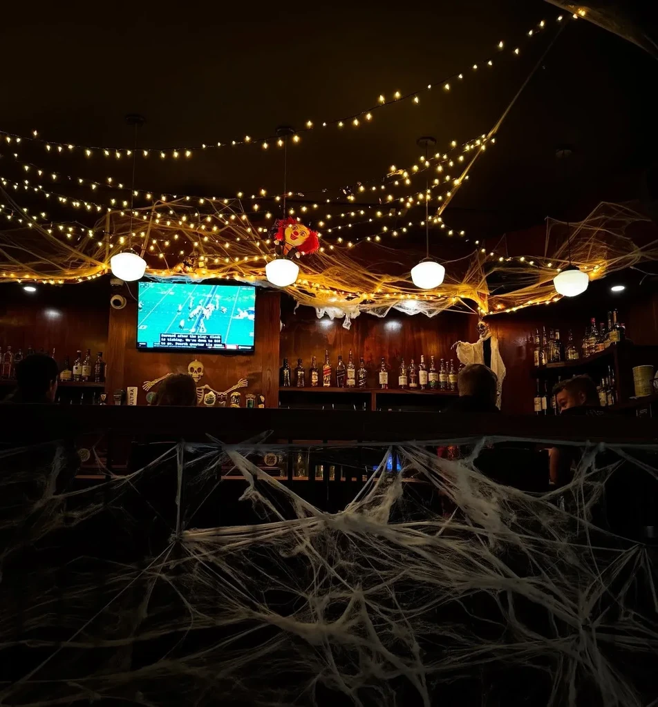 Dimly lit bar heavily decorated for Halloween with sports on TV.