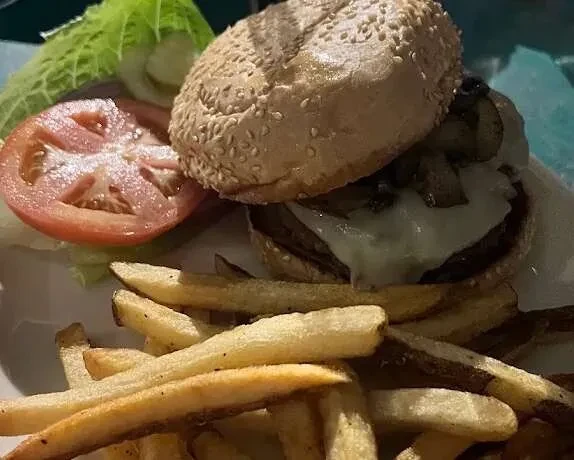 Burger with melted cheese, mushrooms, and golden french fries.
