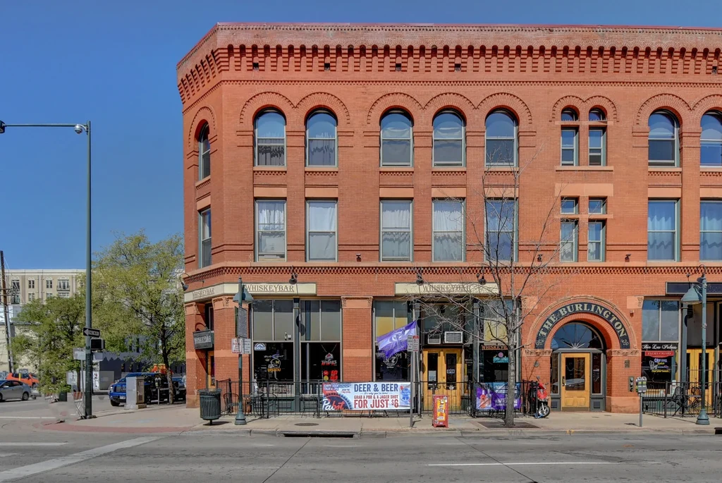 Prominent brick building with a whiskey bar on a sunny street corner.