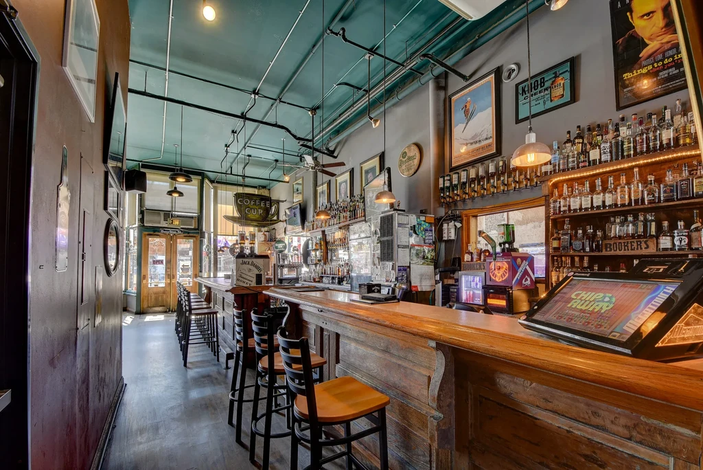 Empty rustic bar interior with liquor shelves and gaming machines.