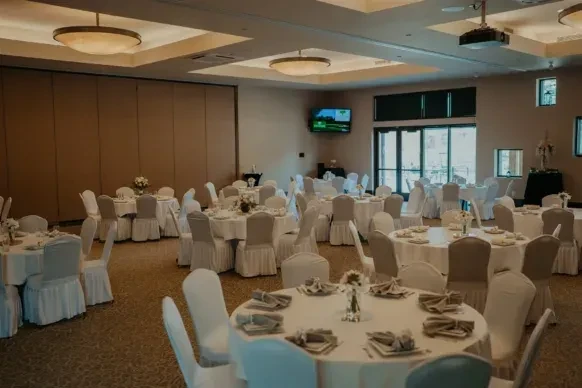 Well-lit formal event space with set round tables.