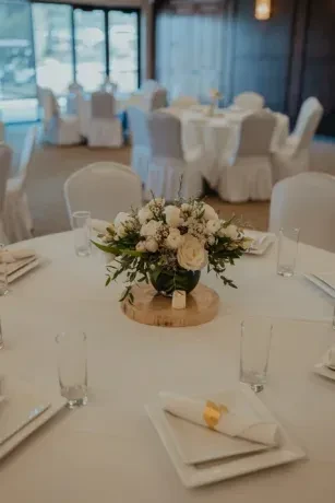 Formal round dining table with white floral centerpiece and settings.