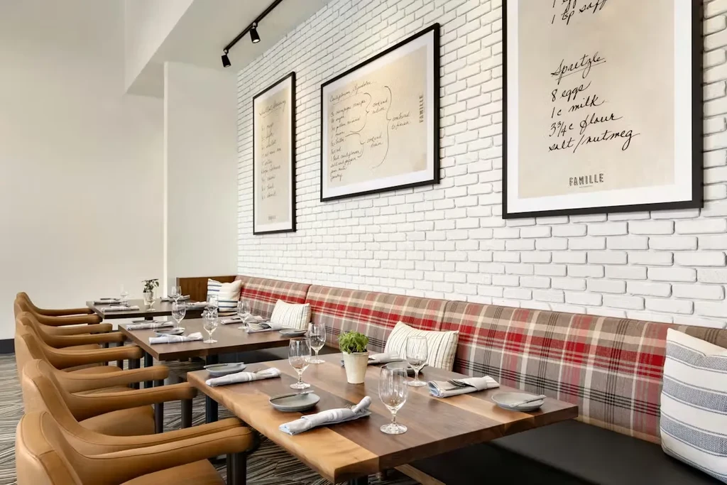 Modern restaurant interior with set tables, leather chairs, and plaid banquette.