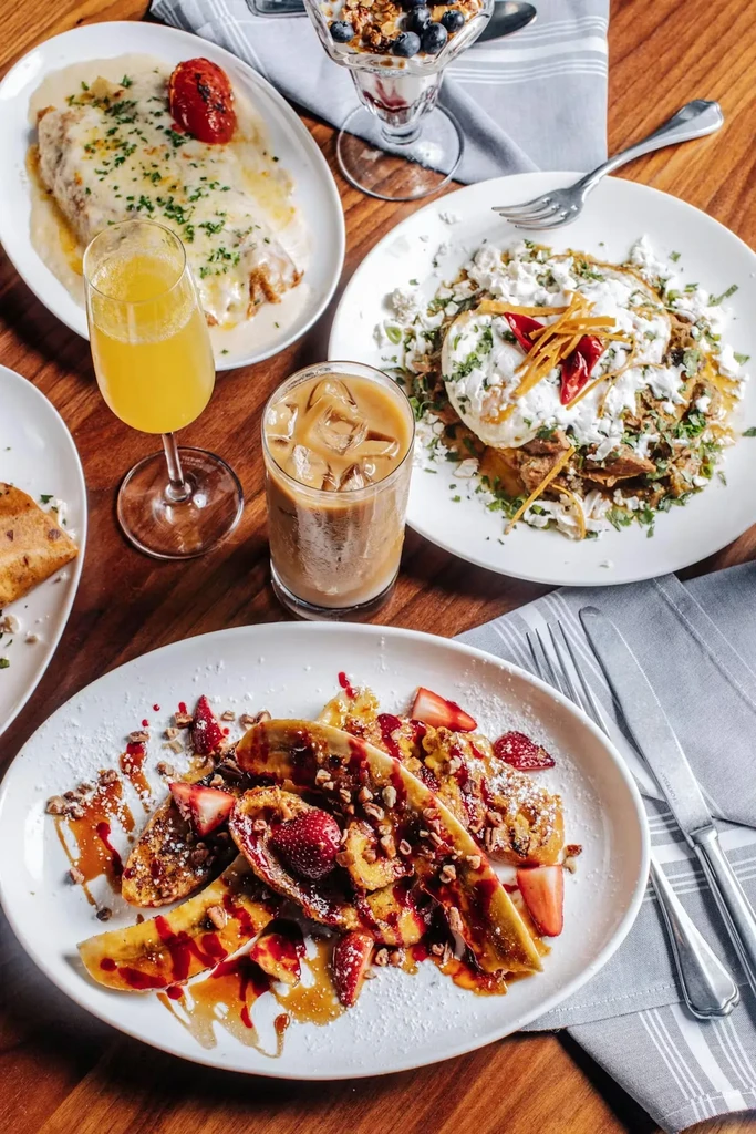 A diverse spread of colorful brunch dishes and drinks on wood.
