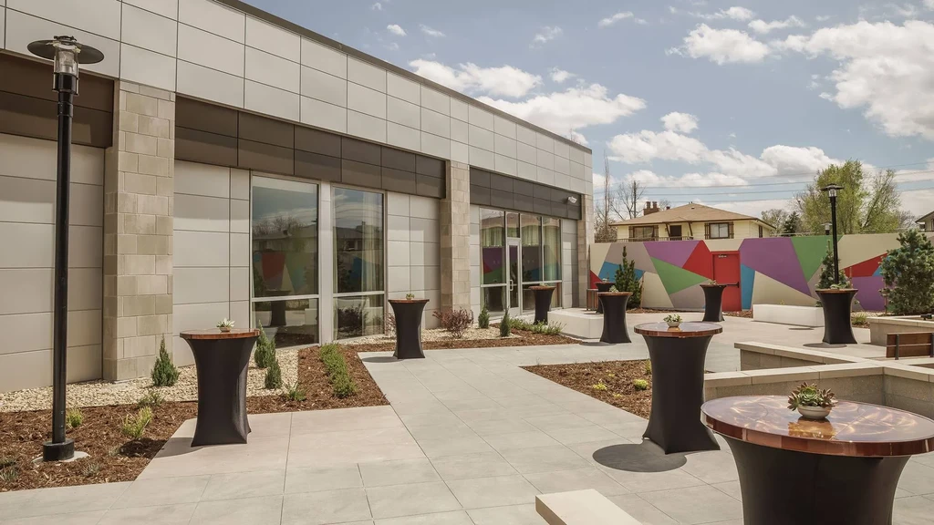 Modern outdoor patio with high-top tables, succulents, and colorful geometric wall.