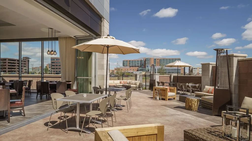 Modern restaurant patio with diverse seating, indoor dining, city view.