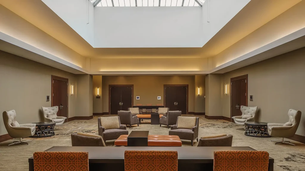 Large, well-lit hotel lounge with skylight and diverse seating.