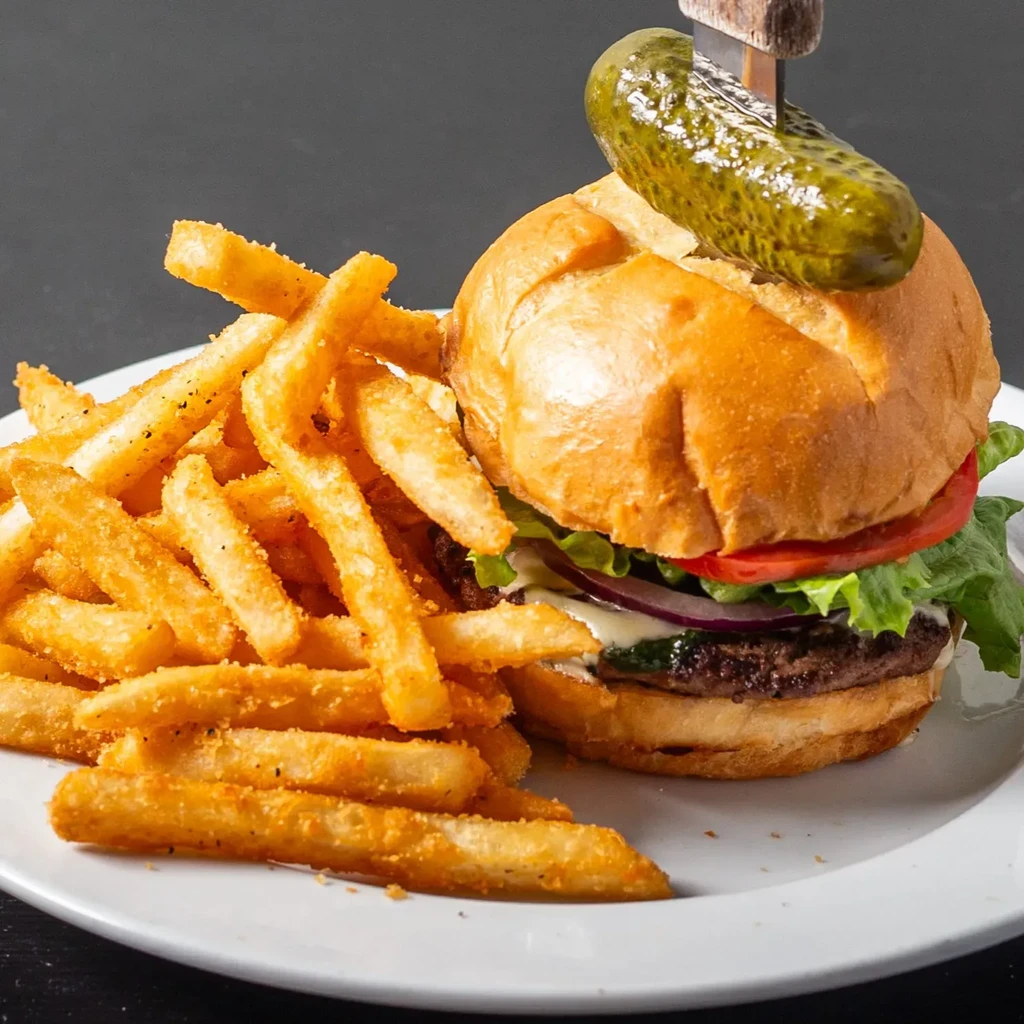 A classic burger with a pickle, melted cheese, and golden fries.
