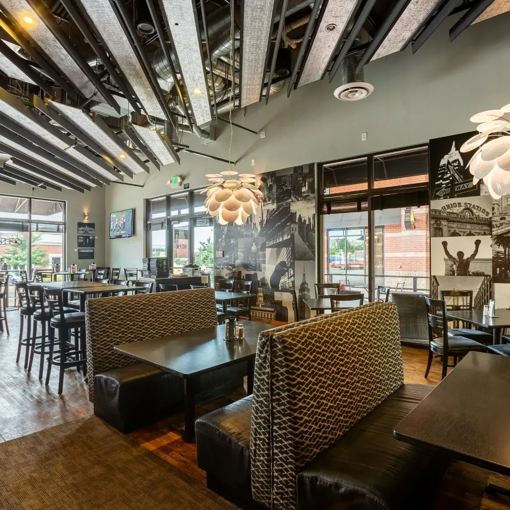 Modern restaurant interior with diverse seating, industrial ceiling, and Rocky mural.