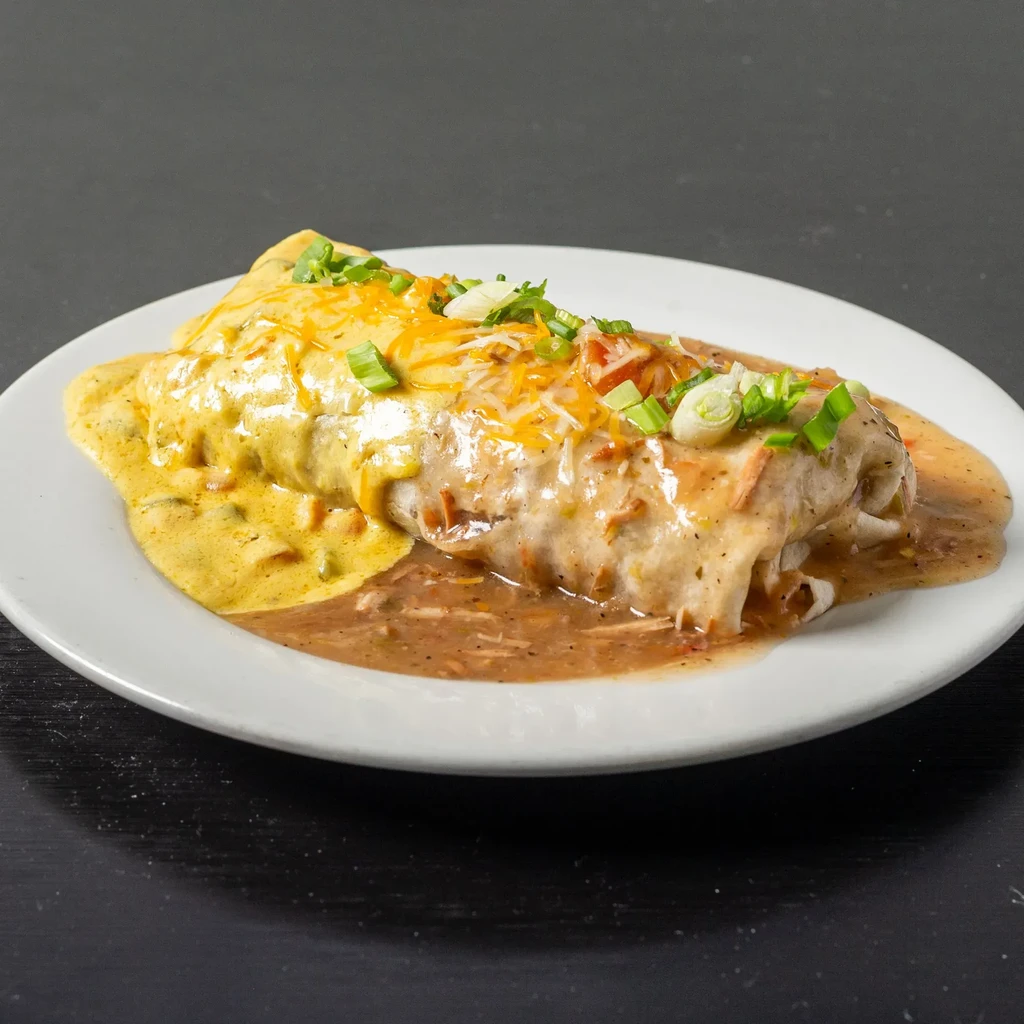 Smothered burrito covered in two sauces, melted cheese, and green onions.