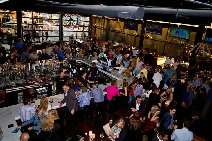Energetic modern restaurant and bar, crowded with customers and bartenders.