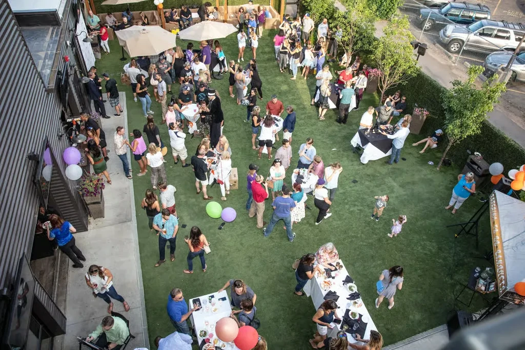High-angle view: A large, lively outdoor gathering on green turf.