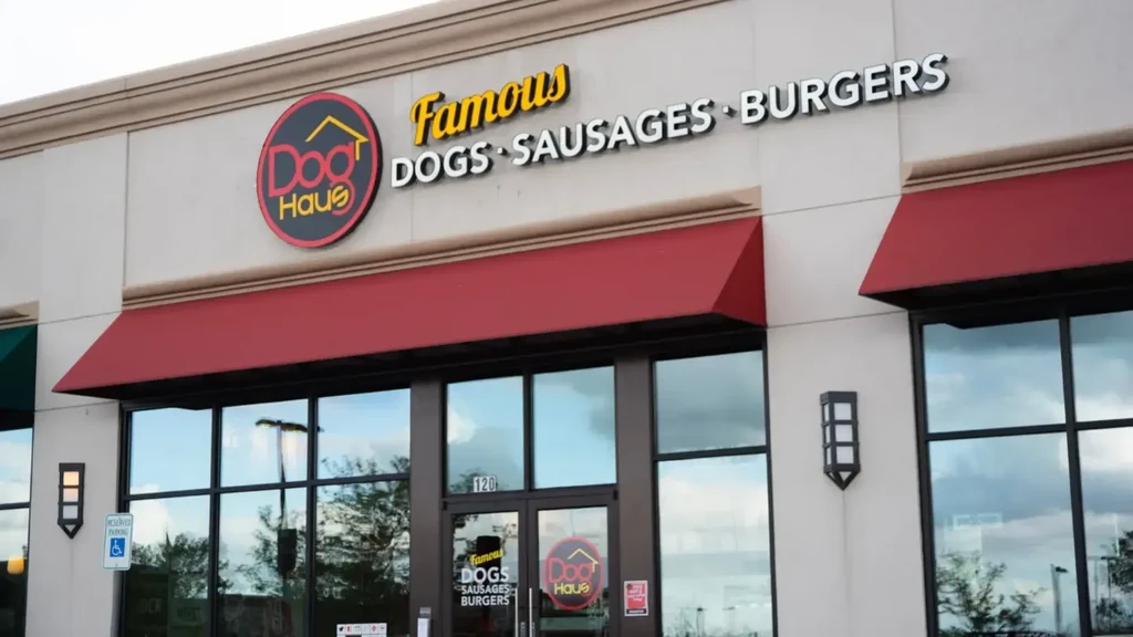 Dog Haus restaurant exterior, featuring its logo, menu, and red awnings.