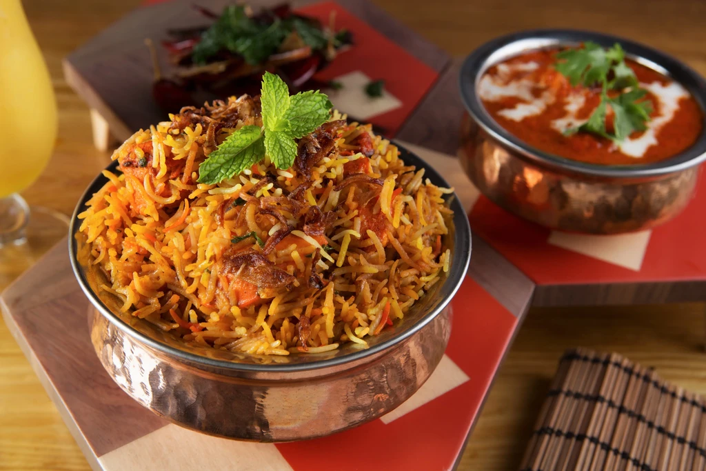 Vibrant Indian biryani and curry in hammered copper bowls.