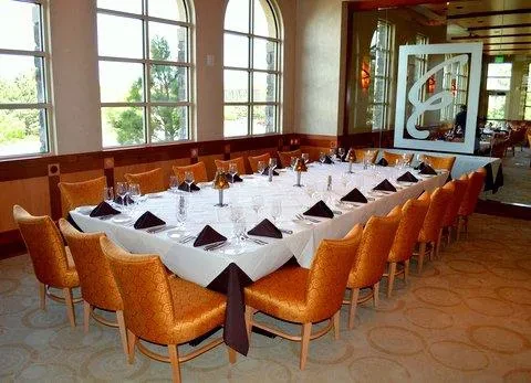 Formal dining room with long set table, scenic view, and 'E' logo.