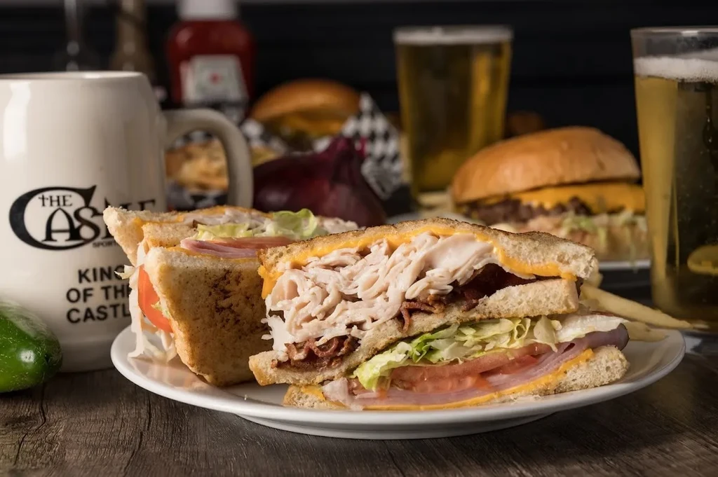 Substantial club sandwich with ham, turkey, bacon, cheese, lettuce, and tomato.