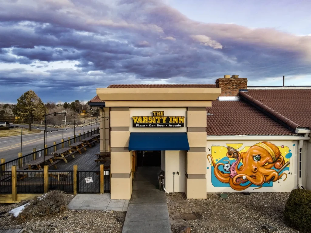 The Varsity Inn restaurant with outdoor patio, blue awning, and octopus mural.