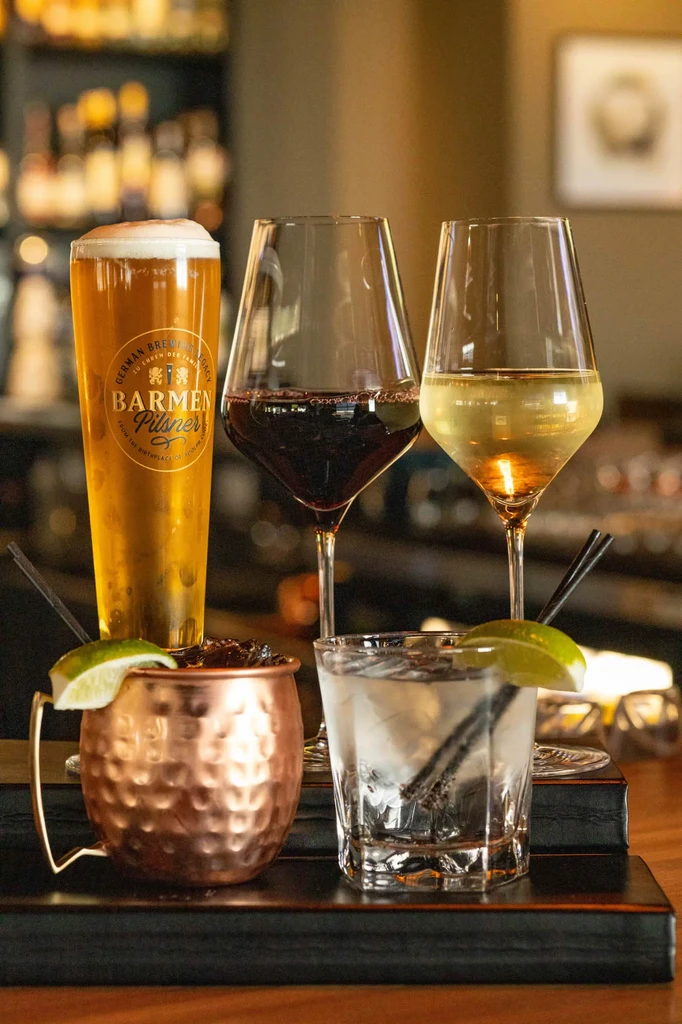 Five alcoholic drinks, including beer, wines, and cocktails, on a bar tray.