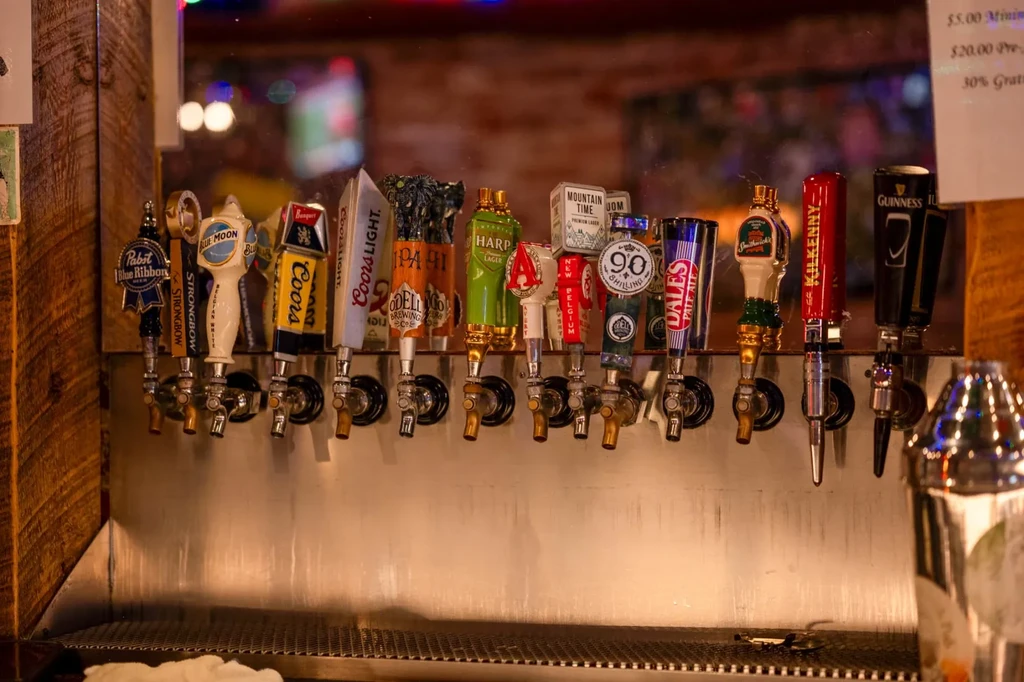 Row of 15 varied beer taps featuring popular brands at a bar.