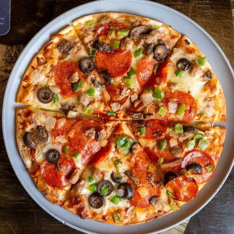 Round pizza with pepperoni, olives, peppers, mushrooms, and sausage.