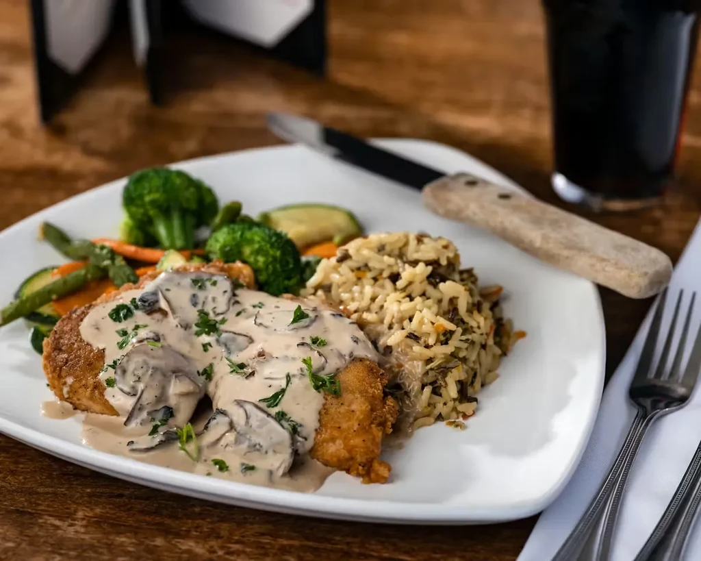 Breaded cutlets topped with creamy mushroom sauce, wild rice, and vegetables.