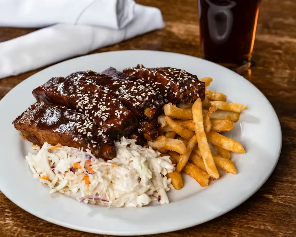 Barbecued ribs with dark sauce, fries, and creamy coleslaw.