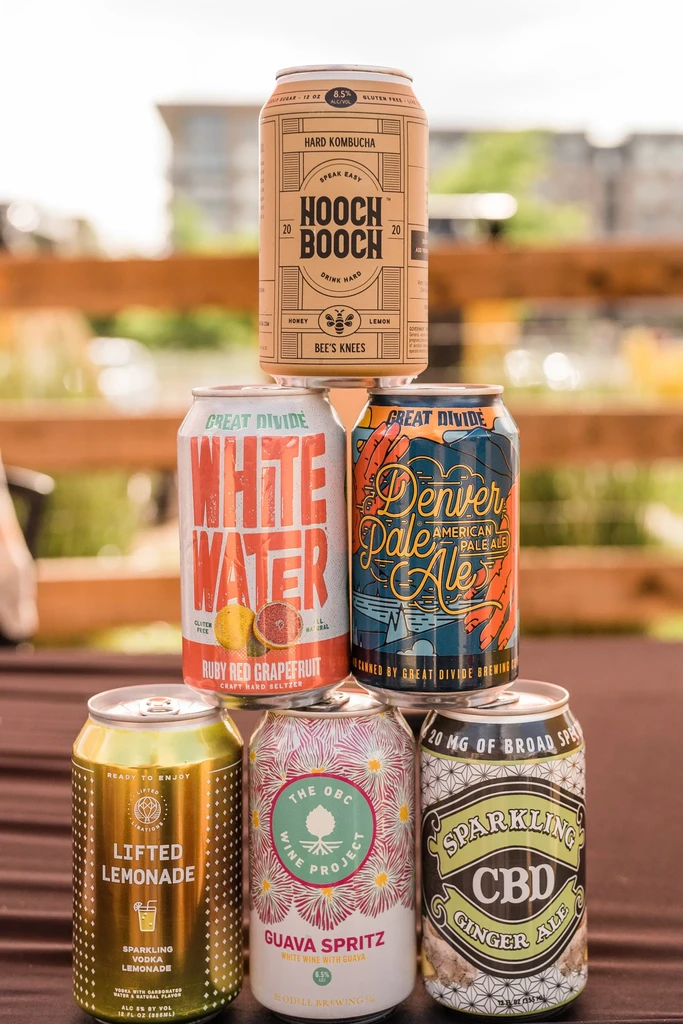 Pyramid of seven different canned beverages displayed outdoors.