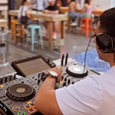 Person from behind wearing headphones operates DJ equipment.