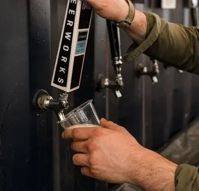Person pouring BEERWORKS beer from a tap into a cup.