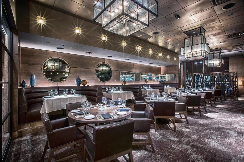 Empty, upscale restaurant dining room with modern decor and set tables.