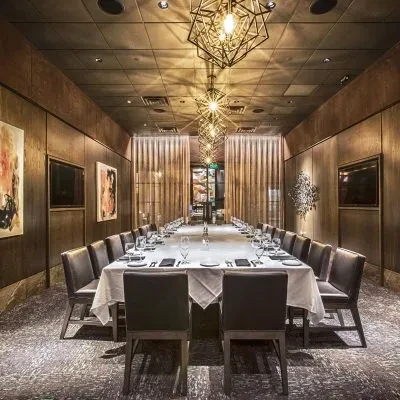Elegant private dining room with long, set table and geometric lights.