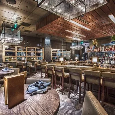 Empty upscale bar and restaurant, warm lighting, dark wood, marble.