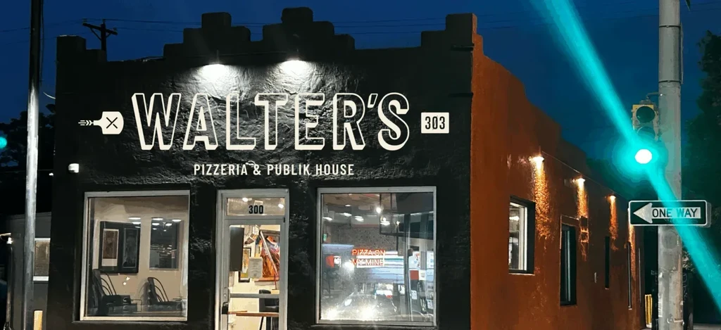 Nighttime exterior of Walter's Pizzeria and Publik House with lit signage.