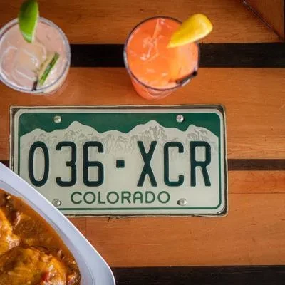 Two cocktails, Colorado license plate, and partial yellow food dish.