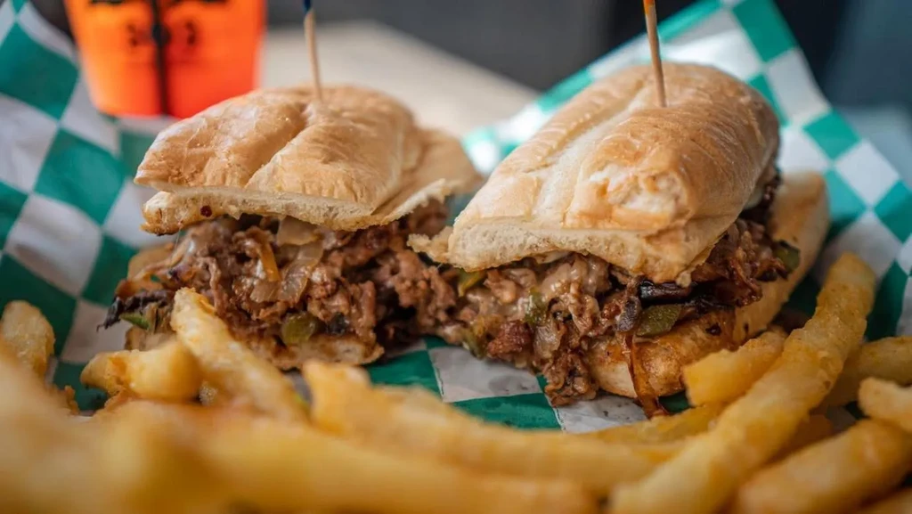Two meat and cheese sandwich halves with melted cheese and fries.