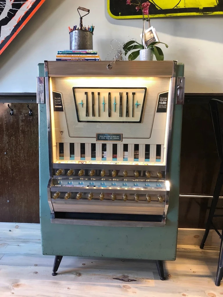 Vintage mint green ART-O-MAT vending machine in a quirky art space.
