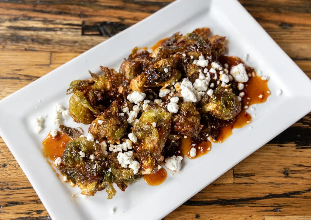 Roasted Brussels sprouts with dark glaze and crumbled white cheese.