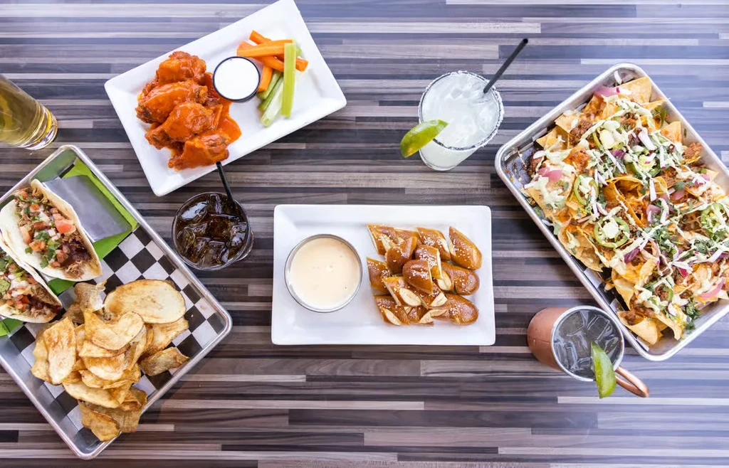 Top-down view of various appetizers and drinks on a wooden table.
