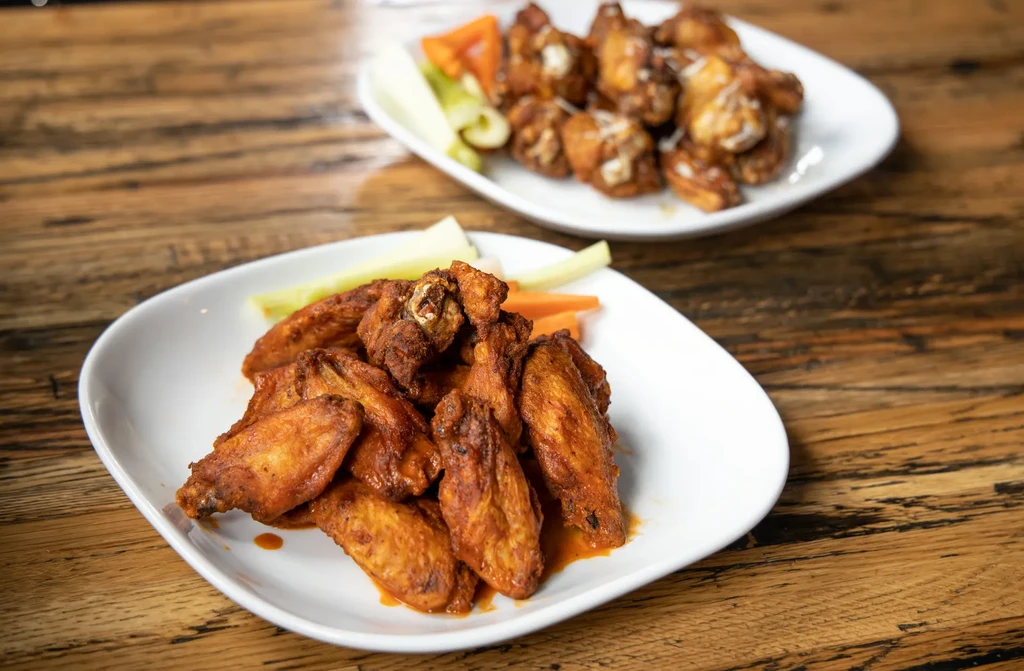 Spicy wings with celery and creamy wings on a wooden table.