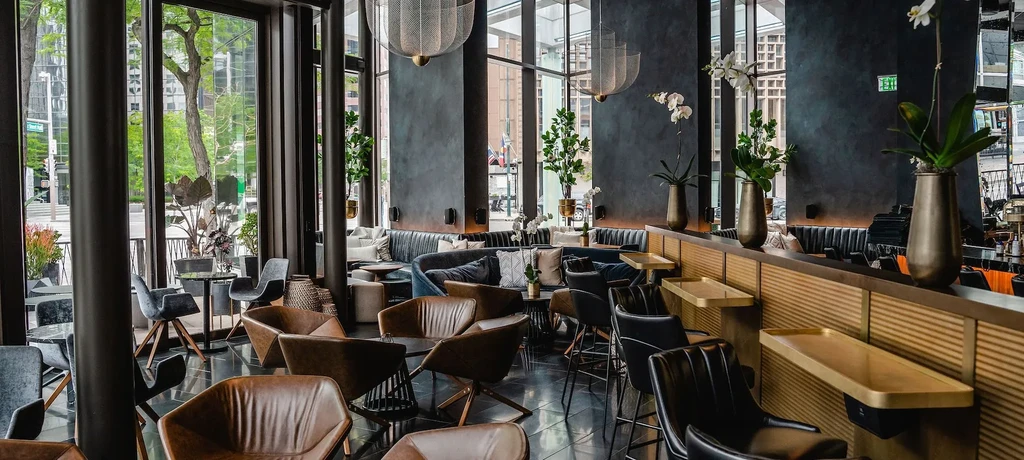 Empty, sophisticated restaurant and bar with varied seating and urban view.