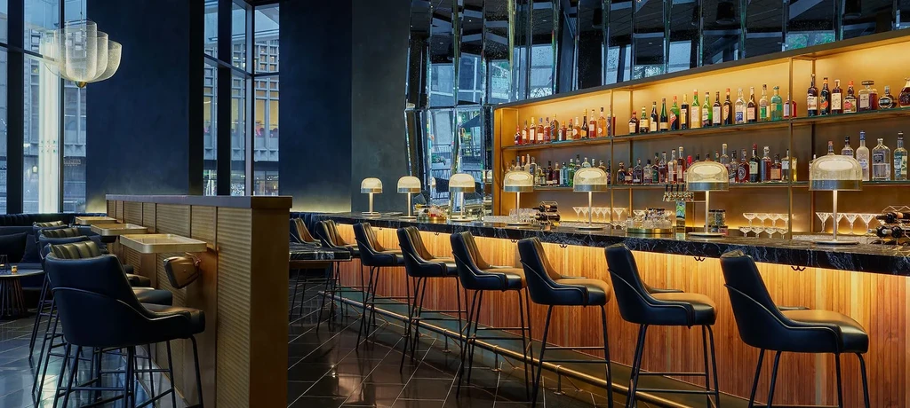 Modern luxury bar with backlit liquor bottles, marble counter, and lounge.