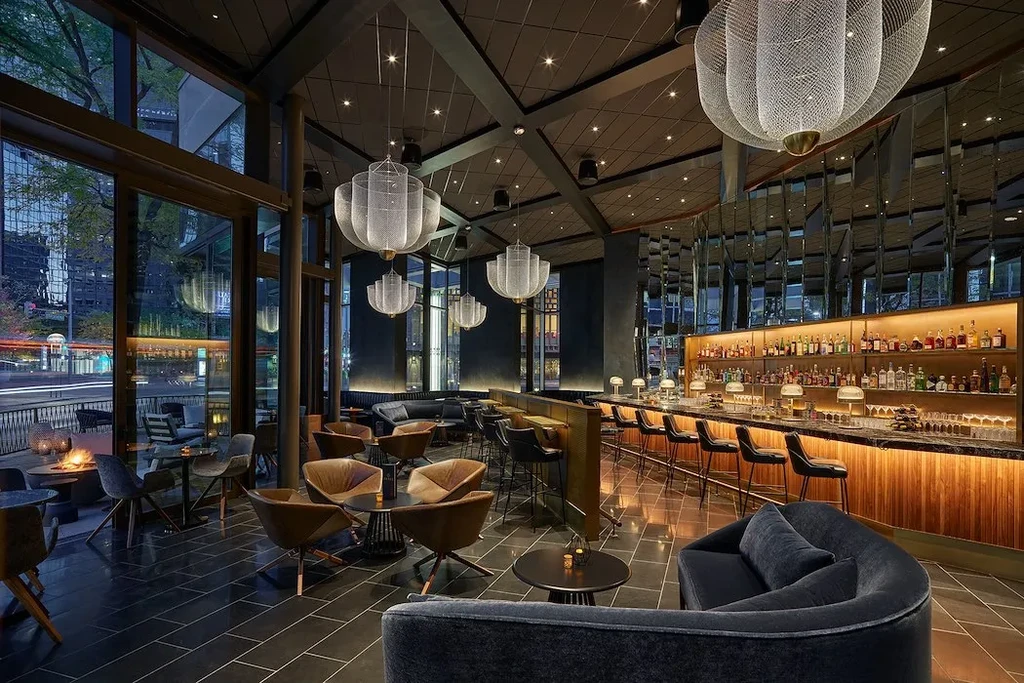 Modern, upscale bar and lounge with illuminated shelves and city view.