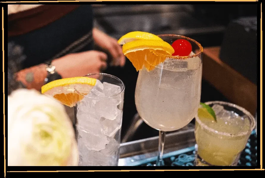 Three elaborately garnished drinks on a bar counter.
