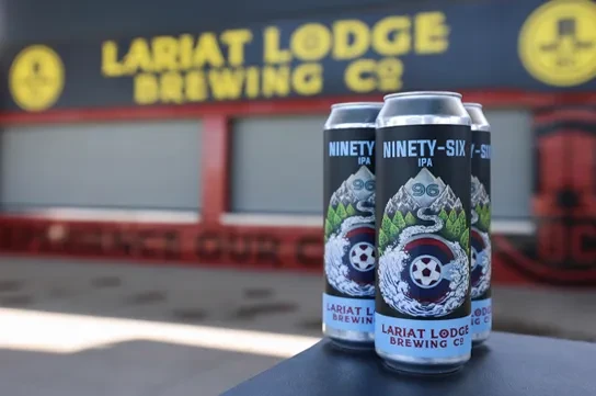 Three Lariat Lodge Brewing Ninety-Six IPA cans, brewery building visible.