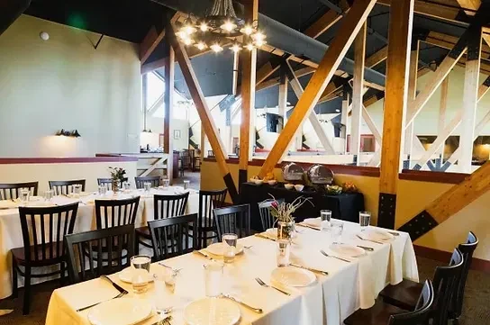 Spacious dining hall with set tables, a buffet, and exposed beams.