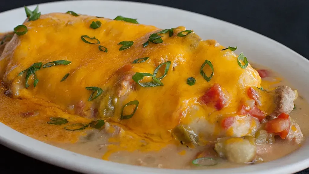Cheesy smothered dish with green onions, tomatoes, and meat.