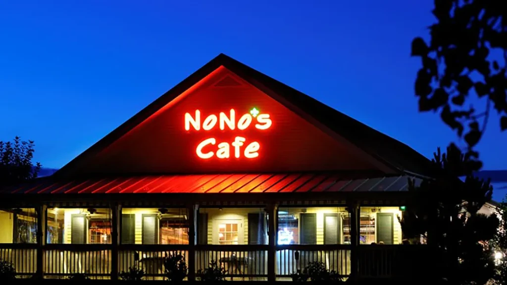 NoNo's Cafe at twilight, glowing sign on a red gabled roof.